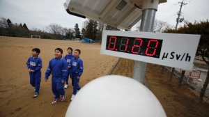 Les élèves marchent près d'un compteur Geiger, mesurer un niveau de 0,12 microsievert par heure de rayonnement, à Omika Elementary School, située à environ 21 km (13 miles) de la Fukushima Daiichi centrale nucléaire de tsunami-paralysé, dans Minamisoma, la préfecture de Fukushima.