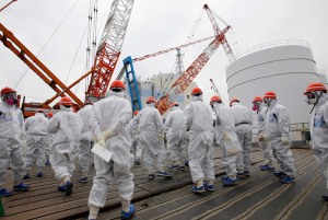 Members of the media and Tokyo Electric Power Co. (TEPCO) employees wearing protective suits and masks walk toward the No. 1 reactor building at the tsunami-crippled TEPCO's Fukushima Daiichi nuclear power plant in Fukushima prefecture March 10, 2014.